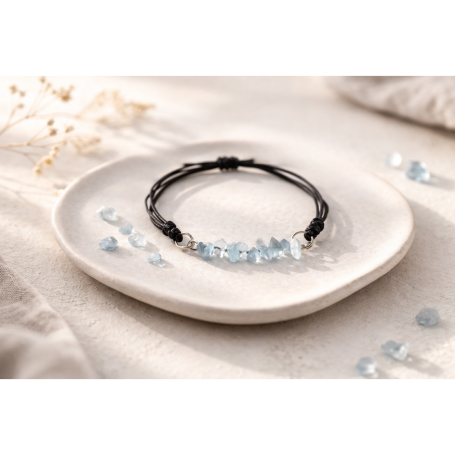 Schwarzes Armband mit blauem Steinbesatz auf einem weißen Teller.