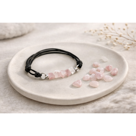 Schwarzes Armband mit rosa Steinen auf einer runden, hellen Unterlage.